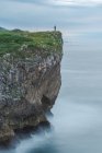 Силует людини, що стоїть на краю скелі біля моря на узбережжі Рібадеселла в похмурий день в Астурії. — стокове фото