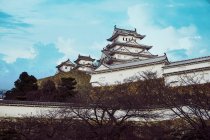 Снизу традиционного замка Химэдзи с изогнутыми крышами на фоне голубого неба в Японии — стоковое фото
