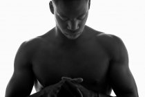 Черное и белое от неэмоционального без рубашки мускулистого молодого черного мужчины со сложенными руками и закрытыми глазами в студии на белом фоне — стоковое фото
