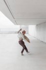 Vista lateral do talentoso dançarino masculino breakdancing em passagem espaçosa na área urbana — Fotografia de Stock