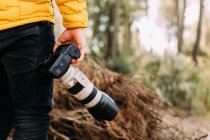 Veduta posteriore di un fotografo anonimo che tiene la sua macchina fotografica in montagna con sfondo sfocato — Foto stock