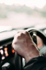 Crop vista di uomo anonimo con la mano su un volante auto su sfondo sfocato — Foto stock