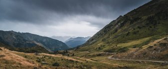 Landscape of Aran valley with majestic green hills and dark gray gloomy sky above — Stock Photo