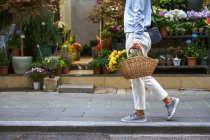 Seitenansicht des Körpers des Mädchens, das beim Gehen einen Blumenkorb trägt — Stockfoto