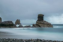 Magnífica vista de rocas rugosas en la playa de Portizuelo bajo el cielo nublado en un día nublado en Asturias - foto de stock