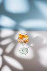 Прозрачный стакан коктейля хайбол украшенный цитрусовыми фруктами и гвоздикой против теней при солнечном свете — стоковое фото