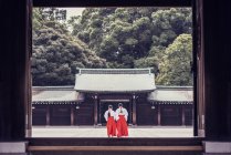 Обратный вид на неузнаваемых людей в традиционном кимоно, стоящих за пределами древнего храма Мэйдзи, расположенного в горах в Сибуя в Токио, Япония — стоковое фото
