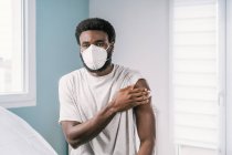 Афроамериканський пацієнт, який тримає бавовну з алкогольною дезінфекцією руки після процедури вакцинації в клініці під час спалаху коронавірусу. — стокове фото