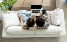 Dall'alto coppia che naviga computer portatile sul divano in camera di casa — Foto stock