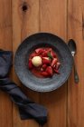 Vue de dessus de savoureuses moitiés de fraises flamboyantes avec glace vanille dans une assiette sur une table en bois — Photo de stock