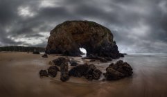 Величественный вид грубых скалистых образований на влажном пляже Пенарронда под облачным небом в Астурии — стоковое фото
