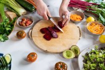 Ernte bis zur Unkenntlichkeit Weibchen schneiden frische Rote Bete mit Messer während der Zubereitung vegetarisches Mittagessen in der Hausküche — Stockfoto