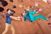 Seitenansicht einer starken weiblichen Kletterwand im Boulderclub unter Aufsicht eines männlichen Instruktors — Stockfoto
