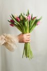 Crop unrecognizable female in romantic dress standing with bunch of tender colorful flowers — Stock Photo