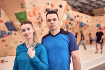 Female and male climbers sitting on floor near artificial wall in contemporary bouldering center while looking at camera — Stock Photo