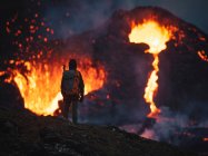 Man explorer observing the magma sparks out of the volcano Fagradalsfjall in Iceland between clouds of smoke — Stock Photo