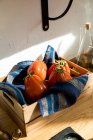 Alto ângulo de tomates vermelhos maduros frescos colocados na bandeja de madeira natural com guardanapo na cozinha doméstica — Fotografia de Stock