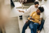 From above of tender multiracial couple lying on couch and spending time together at home — Stock Photo