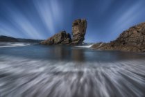 Vue majestueuse de formations rocheuses rugueuses sur la plage humide de Playon de Bayas sous un ciel nuageux dans les Asturies — Photo de stock