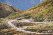 Automóvil moderno conduciendo por sendero polvoriento en verdes montañas de Pirineos con bosque en España - foto de stock