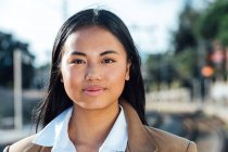 Smiling charming Asian female traveler standing at railroad station and looking at camera — Stock Photo