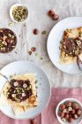 Blick von oben auf leckere Crêpes mit Schokolade und Nüssen auf dem Teller zum Frühstück — Stockfoto