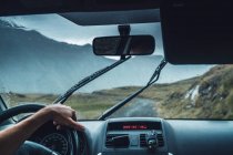 Crop anonymous male driving vehicle on route in majestic Pyrenees mountains during rain — Stock Photo