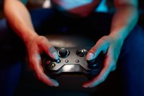 Cortar gamer irreconhecível usando alegria pad e jogar vídeo game no quarto escuro — Fotografia de Stock