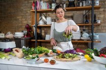 Insalata di verdure di mescolanza femminile felice saporita con foglie di lattuga a tavola in casa di stile di soffitta — Foto stock