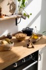 Асорті інгредієнти та посуд, розміщені на дерев'яному столі під час процесу приготування їжі на домашній кухні з білою стіною та мінімалістичним інтер'єром в природному екологічному стилі — стокове фото