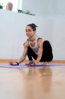 Descalço fêmea em sportswear alongamento enquanto pratica ioga — Fotografia de Stock