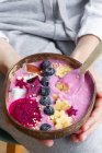 High angle of crop unrecognizable female with power bowl full of fresh banana and pitaya slices with smoothie and blueberries — Stock Photo