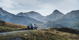 Conduite automobile moderne sur un sentier poussiéreux dans les montagnes verdoyantes des Pyrénées avec forêt en Espagne — Photo de stock