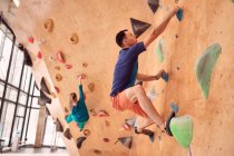 Side view of strong male and female climbers climbing artificial wall in bouldering club — Stock Photo