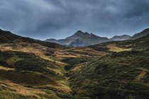 Paisaje del valle de Aran con majestuosas colinas verdes y gris oscuro cielo sombrío por encima - foto de stock