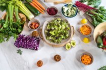 Top view of whole and cut assorted vegetables for salad preparation on marble table — Stock Photo