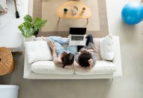 Зверху пара переглядає ноутбук на дивані в кімнаті — стокове фото