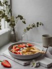 Крупный план вкусной тарелки клубничной каши на столе на кухне — стоковое фото