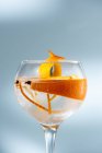 Прозорий келих коктейлю з високих м'ячів, прикрашений цитрусовою плодовою цедрою і гвоздикою проти тіней на сонячному світлі — стокове фото