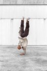 Unrecognizable male dancer showing breakdance movement while balancing on arms and performing Hand Hops on concrete ground in urban area — Stock Photo
