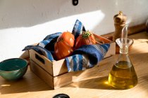 High angle of fresh ripe red tomatoes placed on natural wooden tray with napkin in home kitchen — Stock Photo