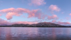 Paysage spectaculaire de lac calme et crête de montagne sous un ciel ensoleillé avec des nuages roses dans le parc national de la Sierra de Guadarrama — Photo de stock