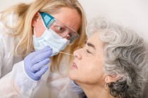Женщина, проводящая тест на ПЦР носа у пациента — стоковое фото