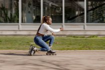 Side view of focused African American female rollerblading along street on sunny day in summer and enjoying weekend in city — Stock Photo