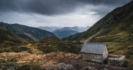Wide angle of small brick building on grassy field in marvellous Pyrenees mountains under overcast sky in Catalonia — Stock Photo