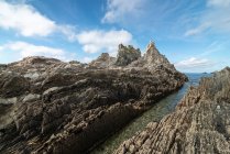 Сценічний вид скелястих утворень на пляжі Геіруа біля спокійного моря під блакитним небом в Астурії. — стокове фото