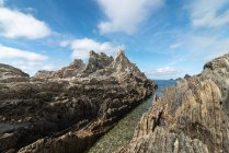 Живописный вид скалистых образований на пляже Гайруа возле спокойного моря под голубым небом в Астурии — стоковое фото