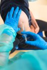 Обрезание женщин-медиков в защитной форме, латексных перчатках и маске для лица вакцинация испанского пациента в клинике во время вспышки коронавируса — стоковое фото