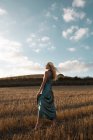 Мирная женщина в элегантном платье, стоящая на сухом поле в сельской местности и закрытые глаза — стоковое фото