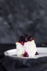Вкусные ломтики печеного чизкейка, увенчанные ягодным джемом, подаются на тарелке на черном фоне — стоковое фото